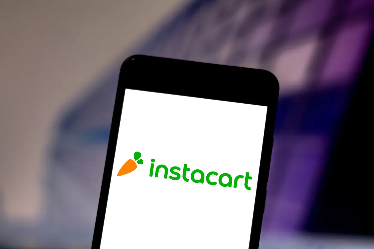 Grocery bags beside a smartphone displaying a delivery app