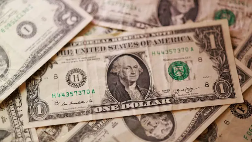 U.S. dollar and British pound banknotes beside a currency trading screen